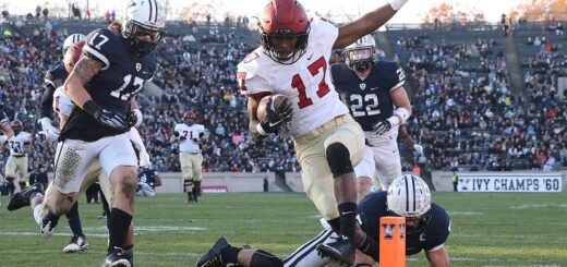 football player reaching the end zone pylon in the football field while being chased by the opposing team